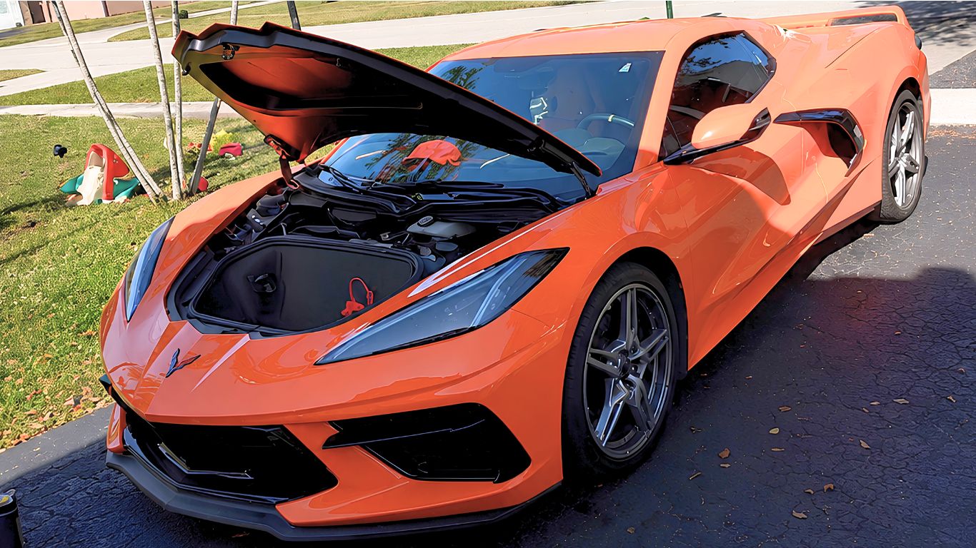 Orange Corvette with the front hood open, parked on a lawn