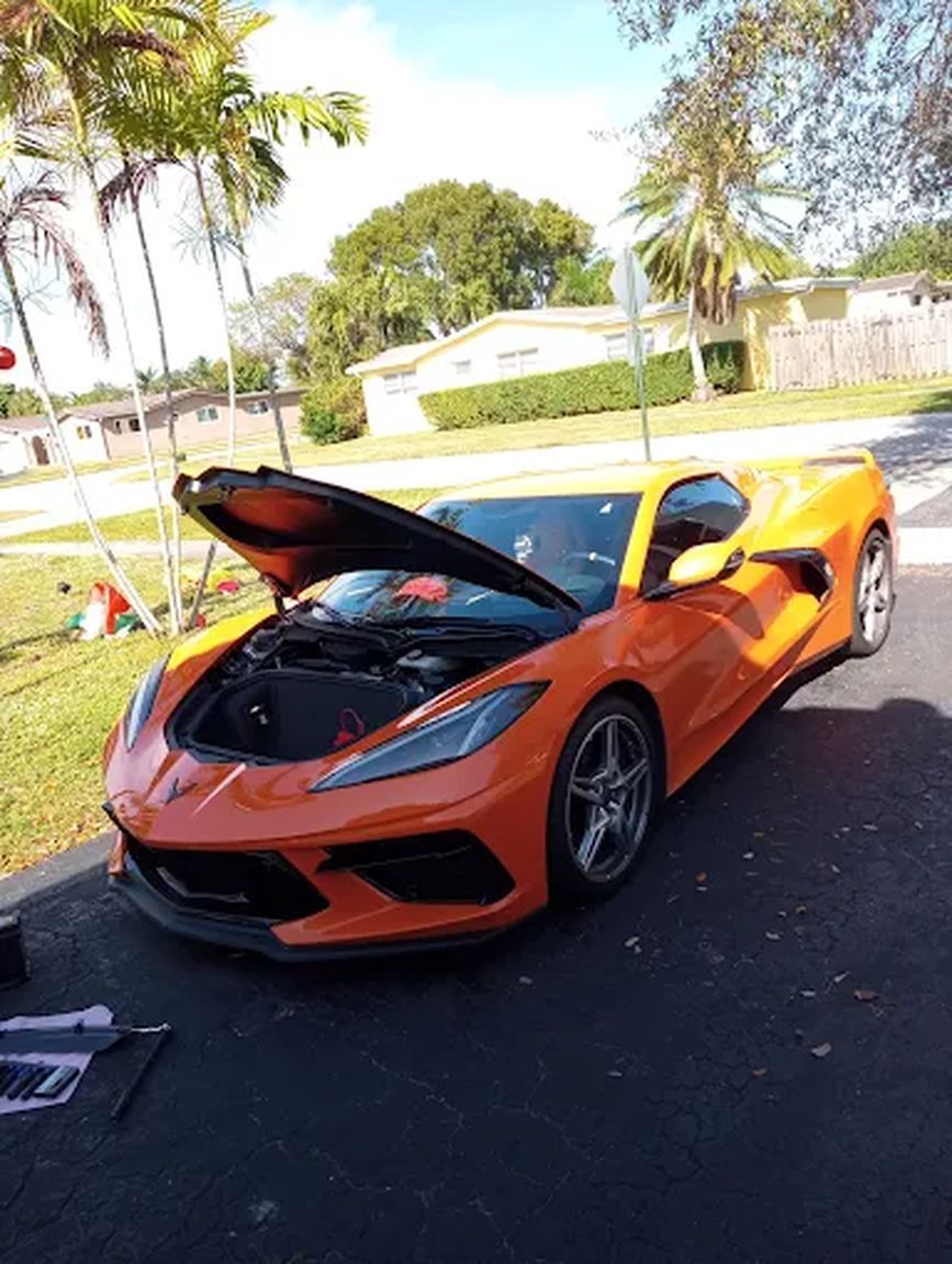 Orange Corvette with the hood open and tools beside it