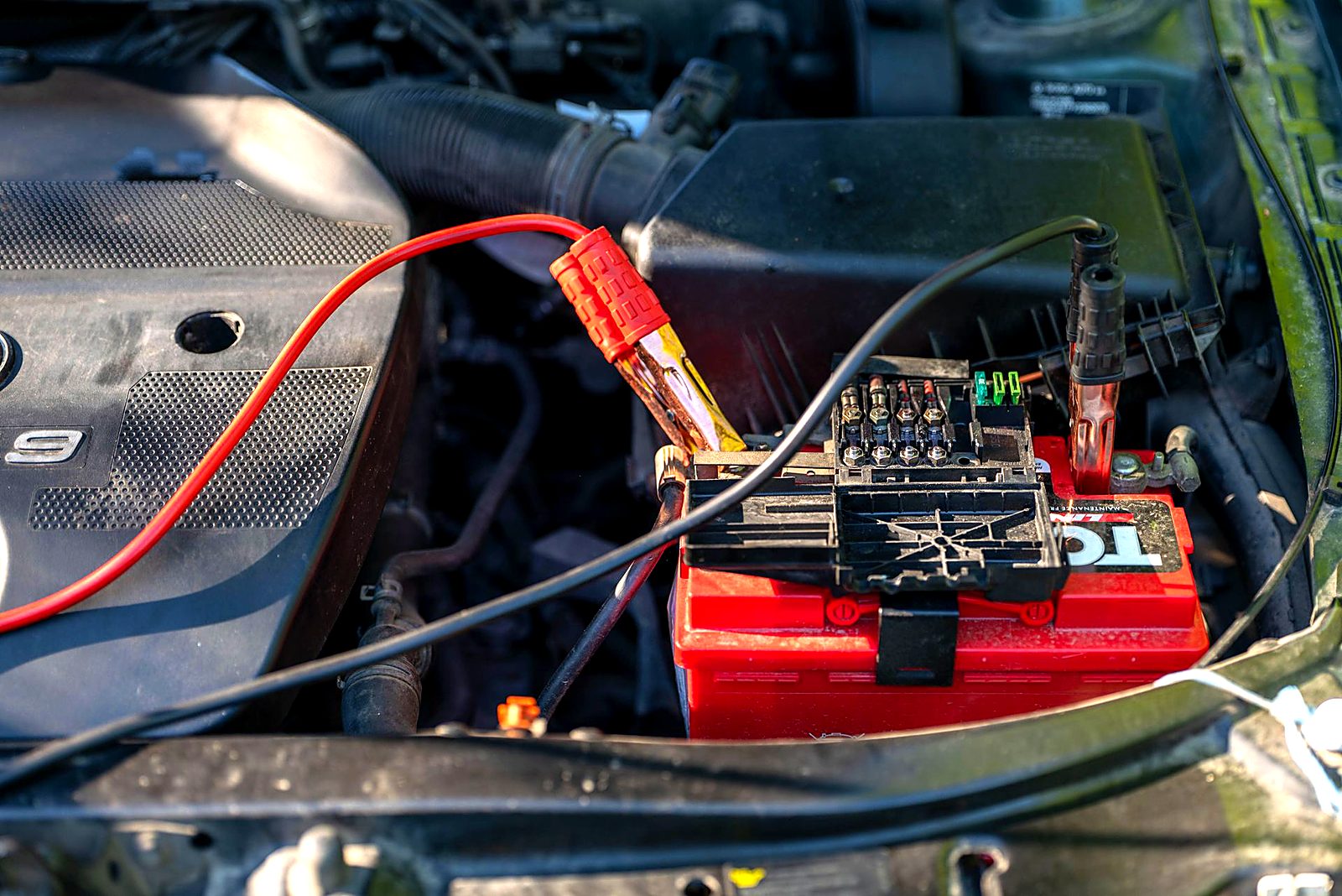 Jump pack clamped to a car battery under the hood