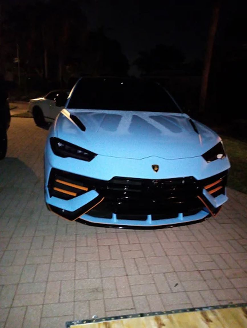 Light blue Lamborghini parked on a driveway at night