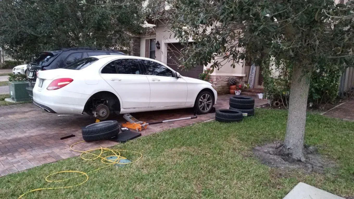White Mercedes on a lawn with a tire change in progress