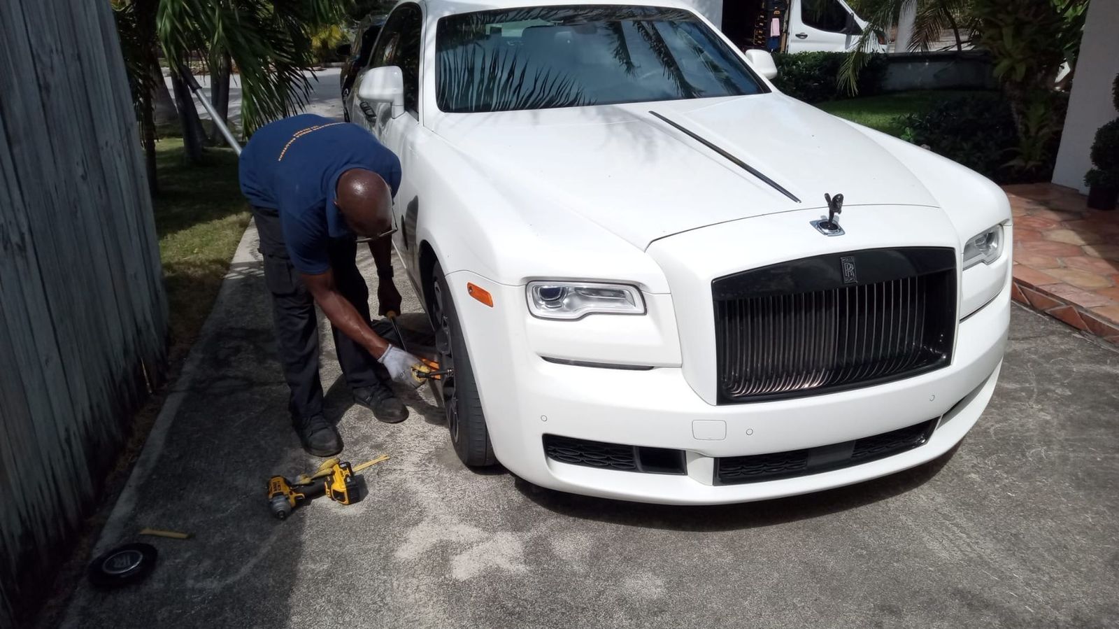 Tire work on a white Rolls-Royce in a driveway