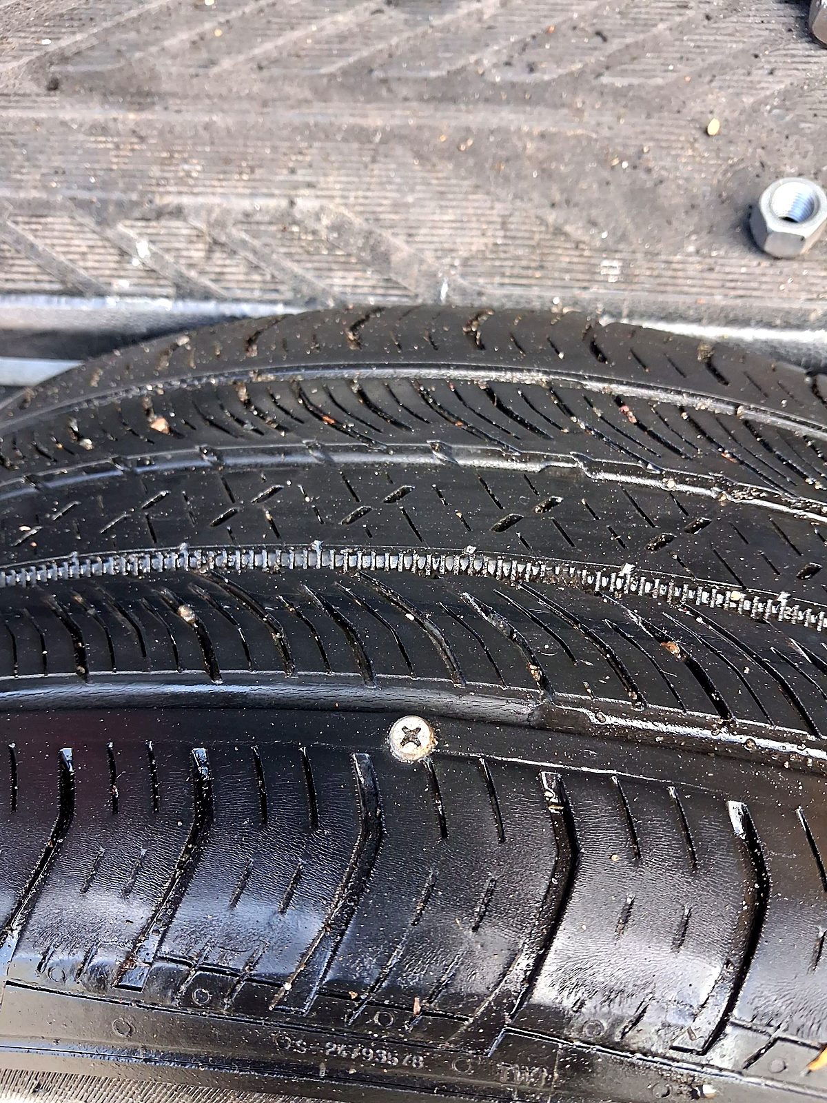 Close up of a screw stuck in a tire tread
