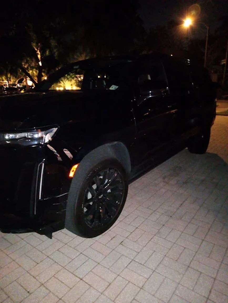 Black SUV on a brick driveway at night