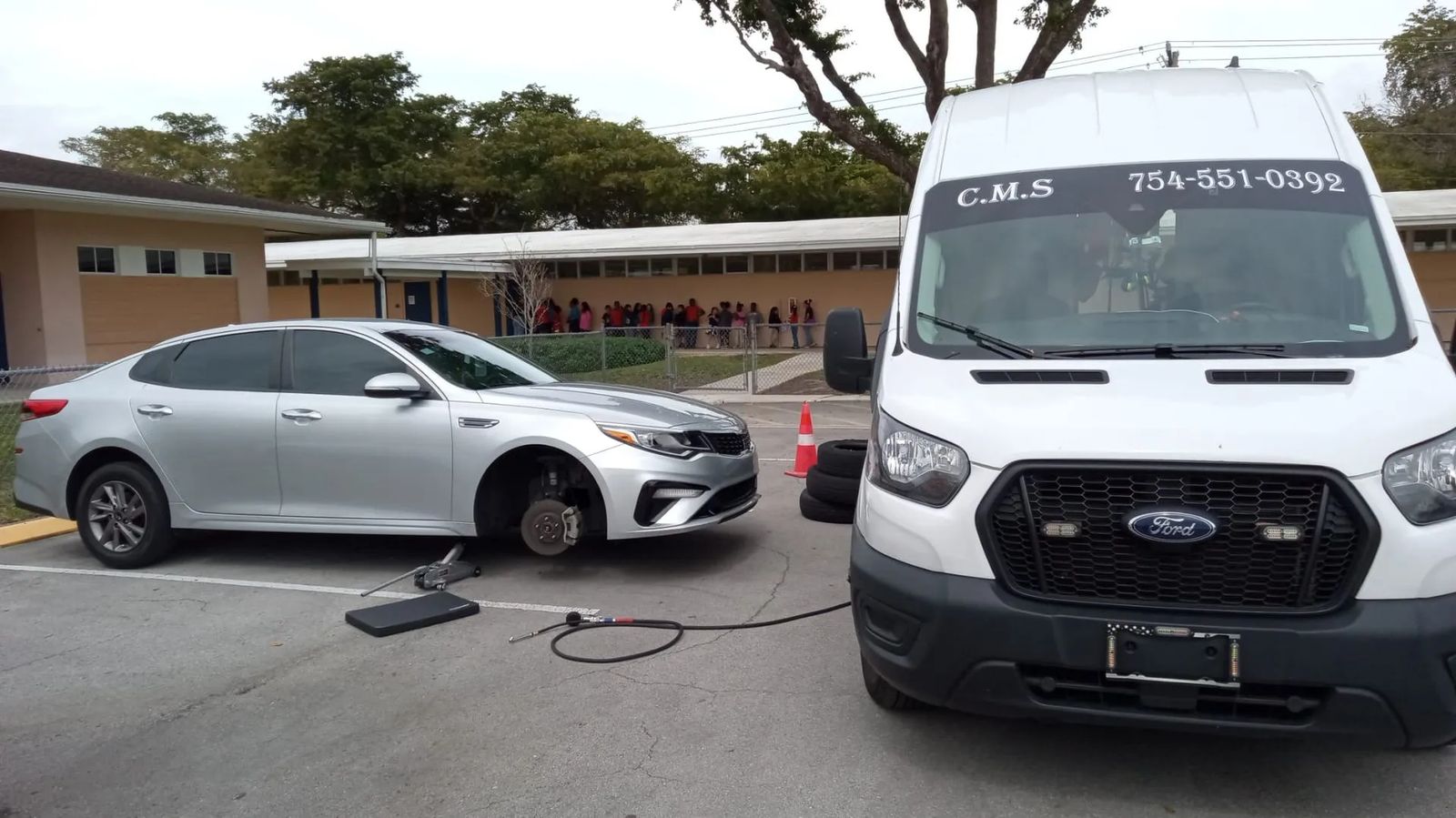 Service van parked beside a silver sedan, tools set out on the pavement