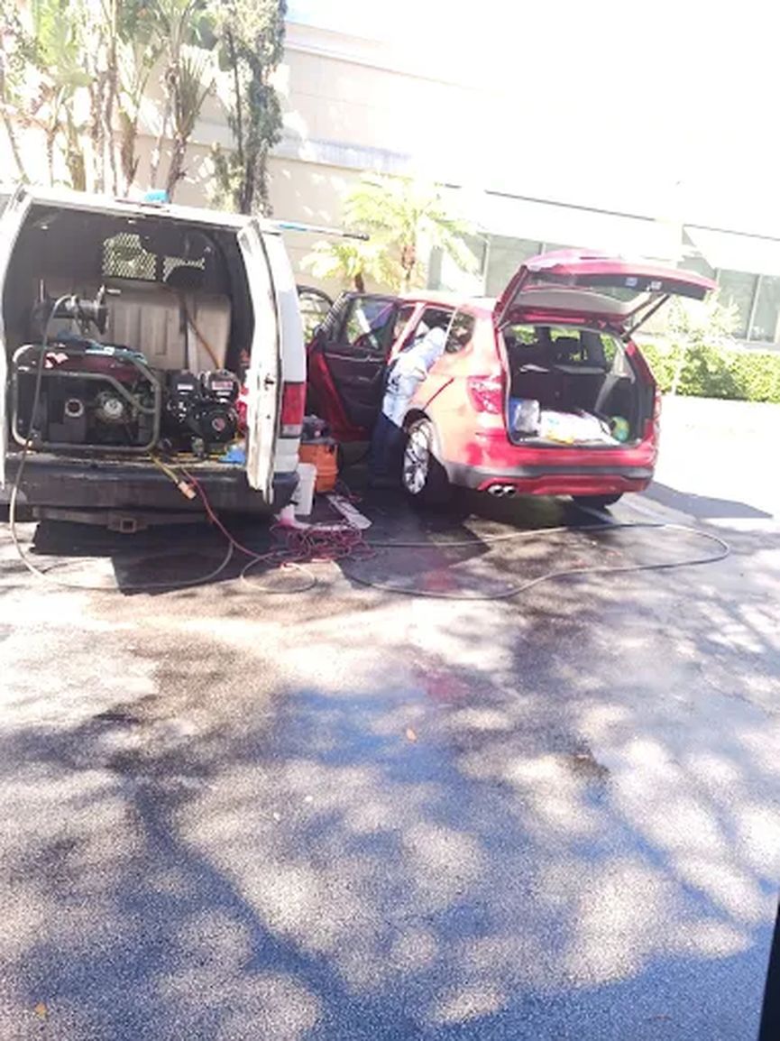 Service van with its doors open next to a red car in a parking lot